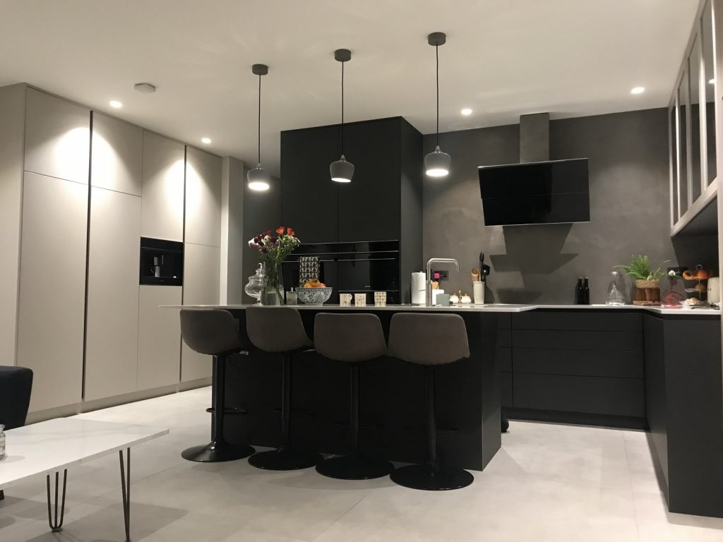 Modern black kitchen with central island and contrasting pantry cupboards in a light, complementary colour